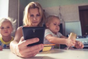 maman avec un smartphone et enfant sur les genoux